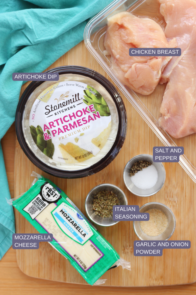 top down image showing a clear container filled with chicken breast sitting on a wooden table top with Stonemill Kitchens artichoke and parmesan dip, salt and pepper, garlic and onion powder, Italian seasoning, and mizzarella cheese from Kroger