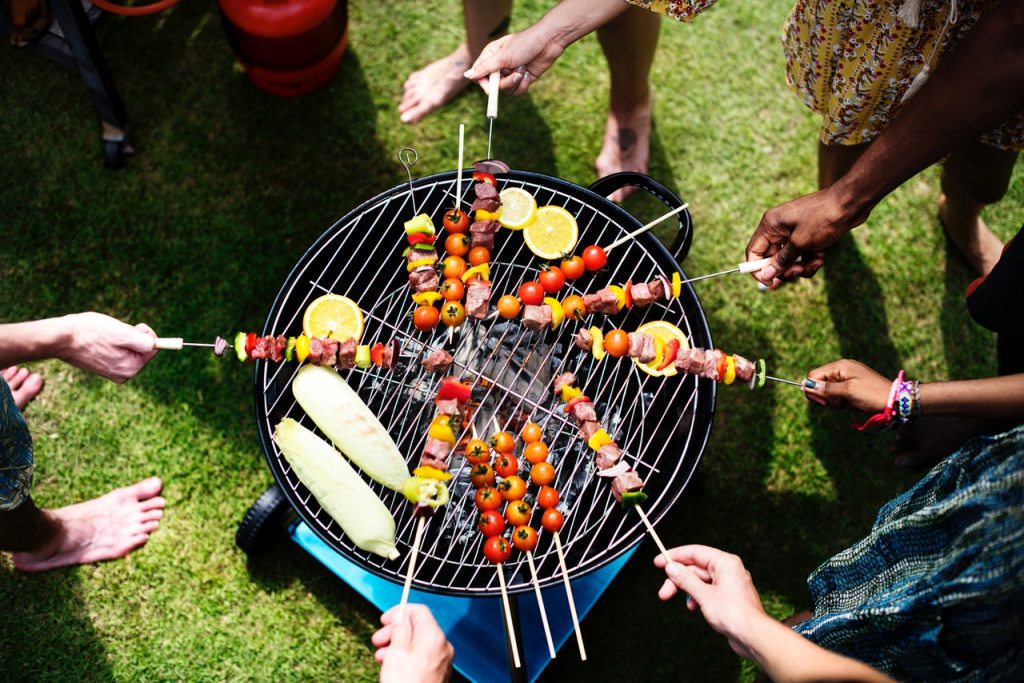 People barbecuing skwered meats on the best portable grill